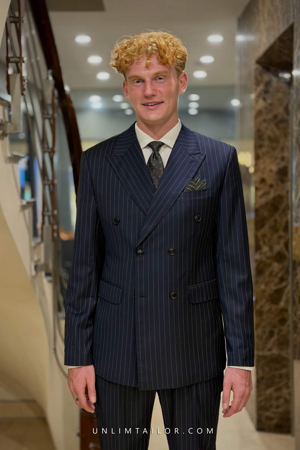 A dark navy blue double-breasted suit with a fine pinstripe pattern, tailored by Unlimtailor Hanoi. - detail images