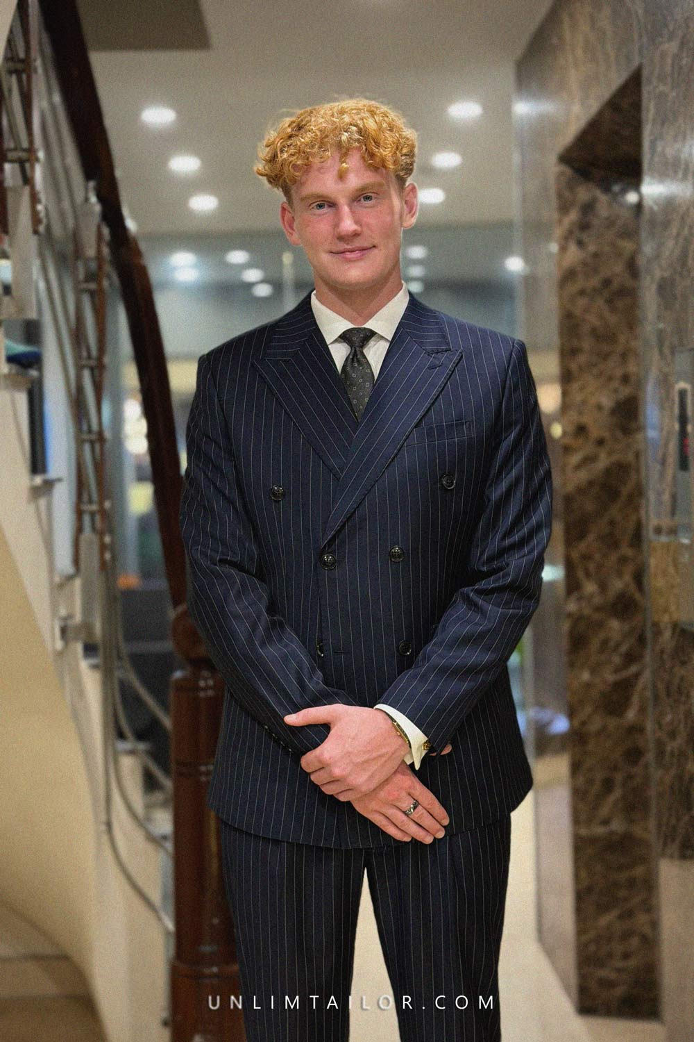 A dark navy blue double-breasted suit with a fine pinstripe pattern, tailored by Unlimtailor Hanoi.