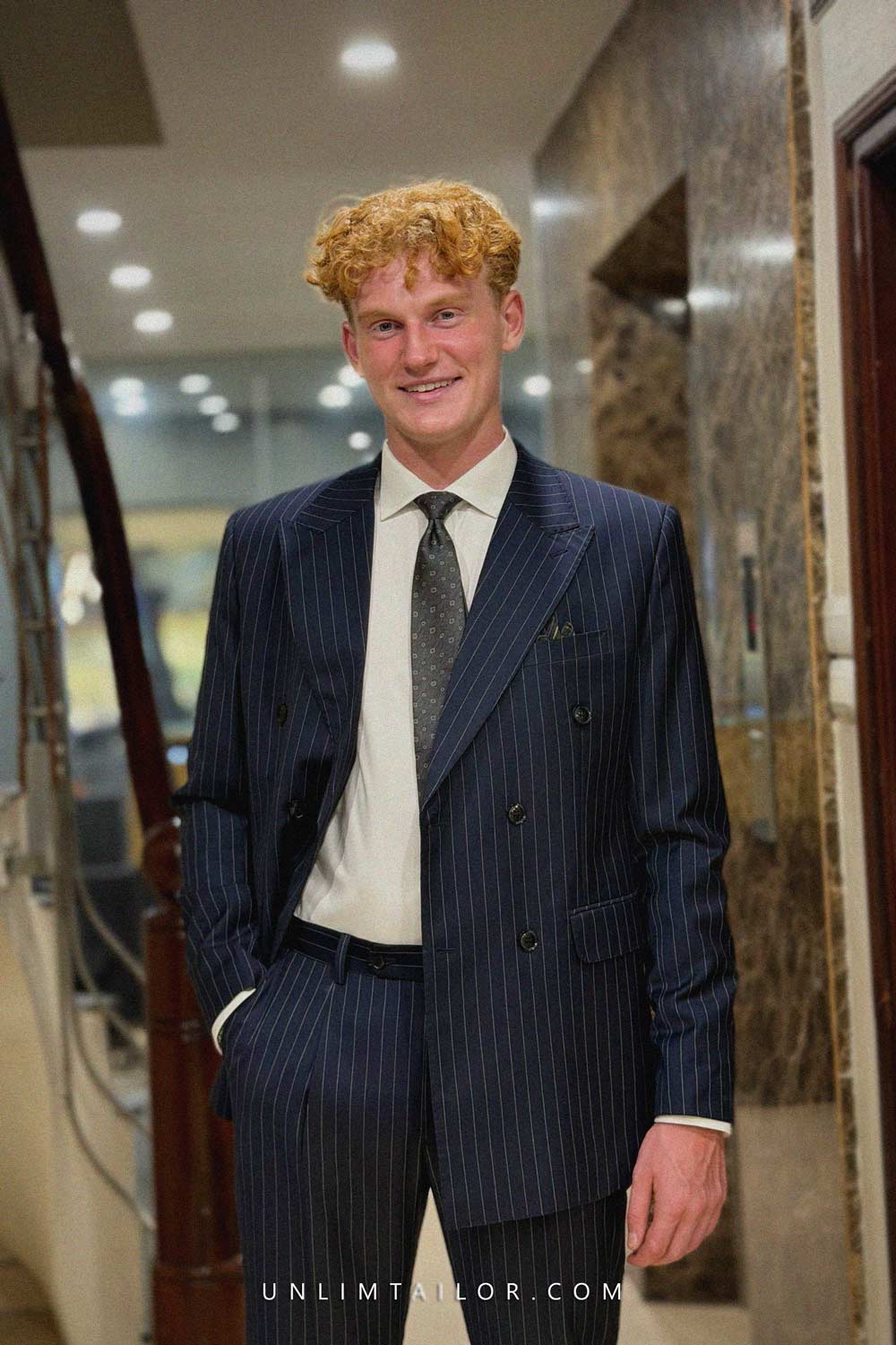 A dark navy blue double-breasted suit with a fine pinstripe pattern, tailored by Unlimtailor Hanoi. - detail images
